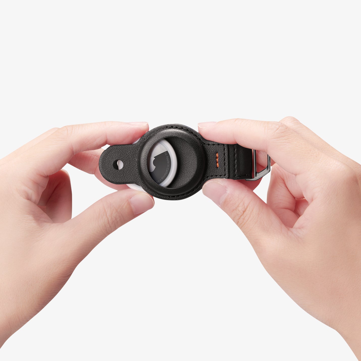 AHP09660 - Apple AirTag Valentinus Pro in Black showing a person carefully inserting the AirTag inside the case