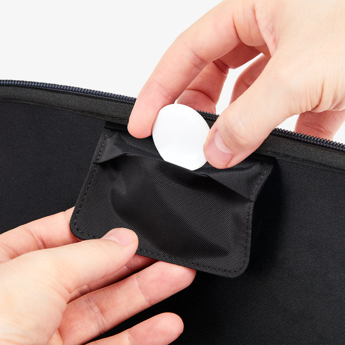 AGP10204 - Nintendo Switch 2 Klasden Pouch Renewed in Charcoal Gray showing a person holding the AirTag placing it inside a small pocket