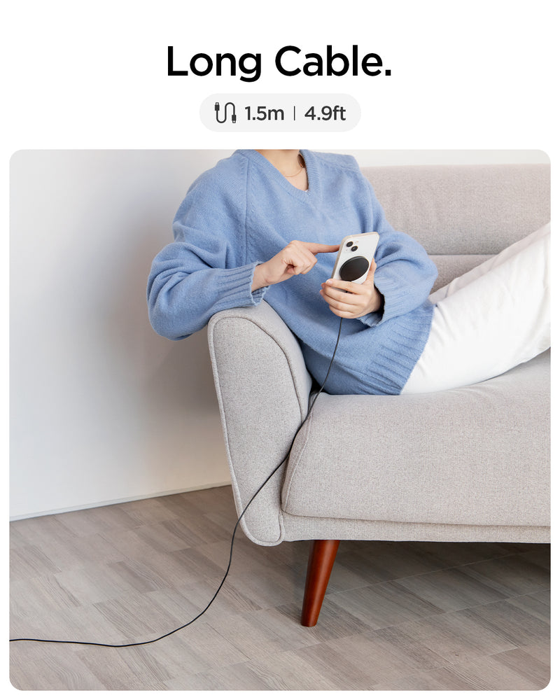 ACH04238 - ArcField™ Magnetic 7.5W Wireless Charger PF2101 (MagFit) in Black showing the Long Cable, 1.5m | 4.9ft. A woman sitting while holding a device attached to a wireless charger away from electric outlet