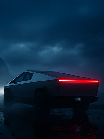 Tesla Cybertruck side and back view with headlights on facing a mountain