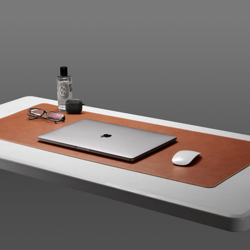 APP04763 - LD302 Desk Pad in brown showing the desk pad on a white table with laptop, mouse and glasses on top