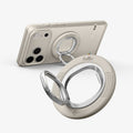 AMP11738 - Angled close-up of a phone with the Spigen Classic LS MagSafe ring propped up as a stand, with a second ring attachment shown separately in the foreground