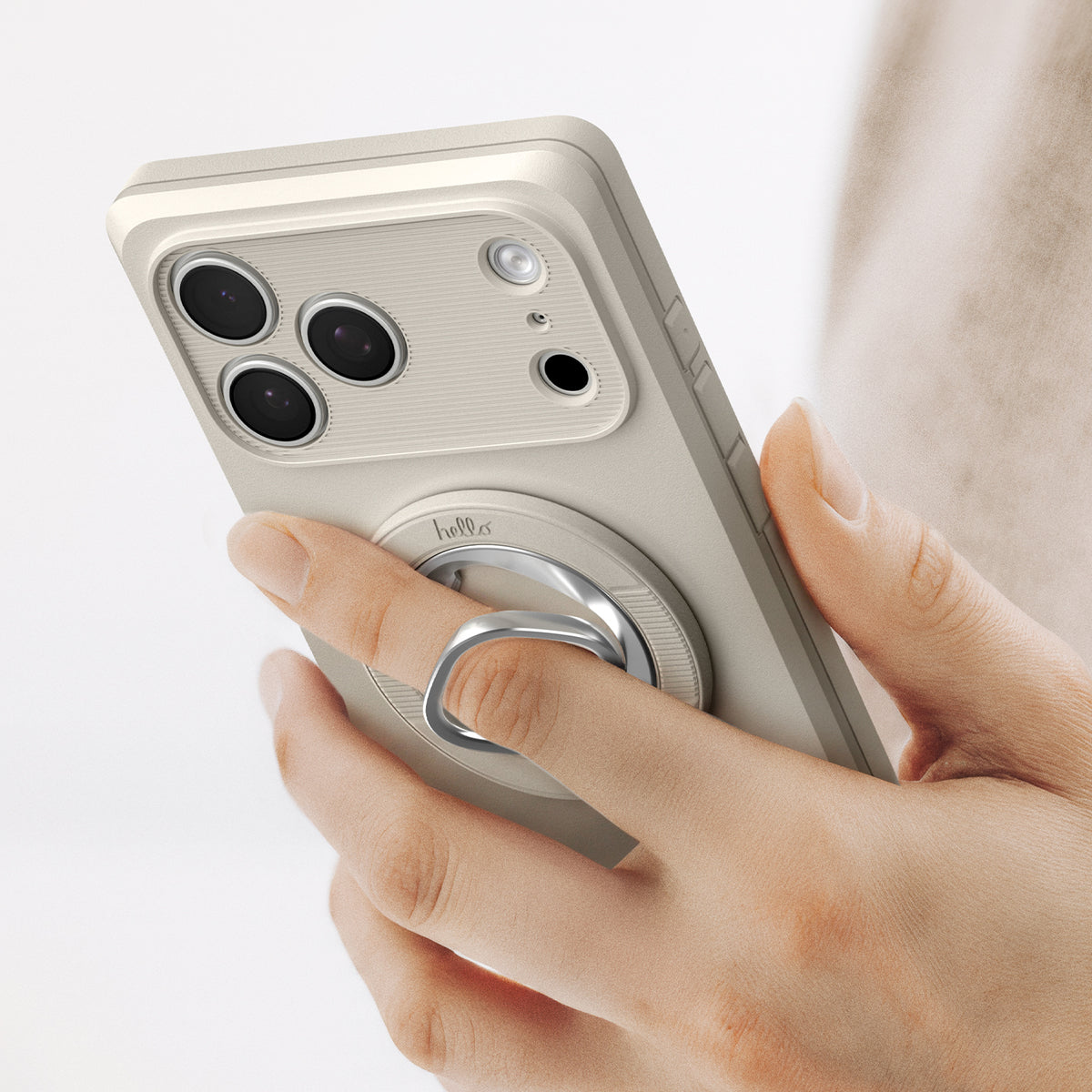 AMP11738 - Hand holding a phone by slipping a finger through the Spigen MagSafe ring attachment on the back