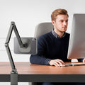 ACS11623 - Man working at a desk with an iPad Mini in the clear white Spigen case mounted on an adjustable articulating arm