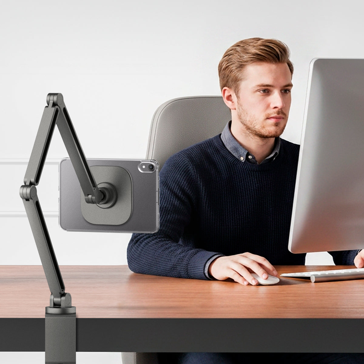 ACS11623 - Man working at a desk with an iPad Mini in the clear white Spigen case mounted on an adjustable articulating arm