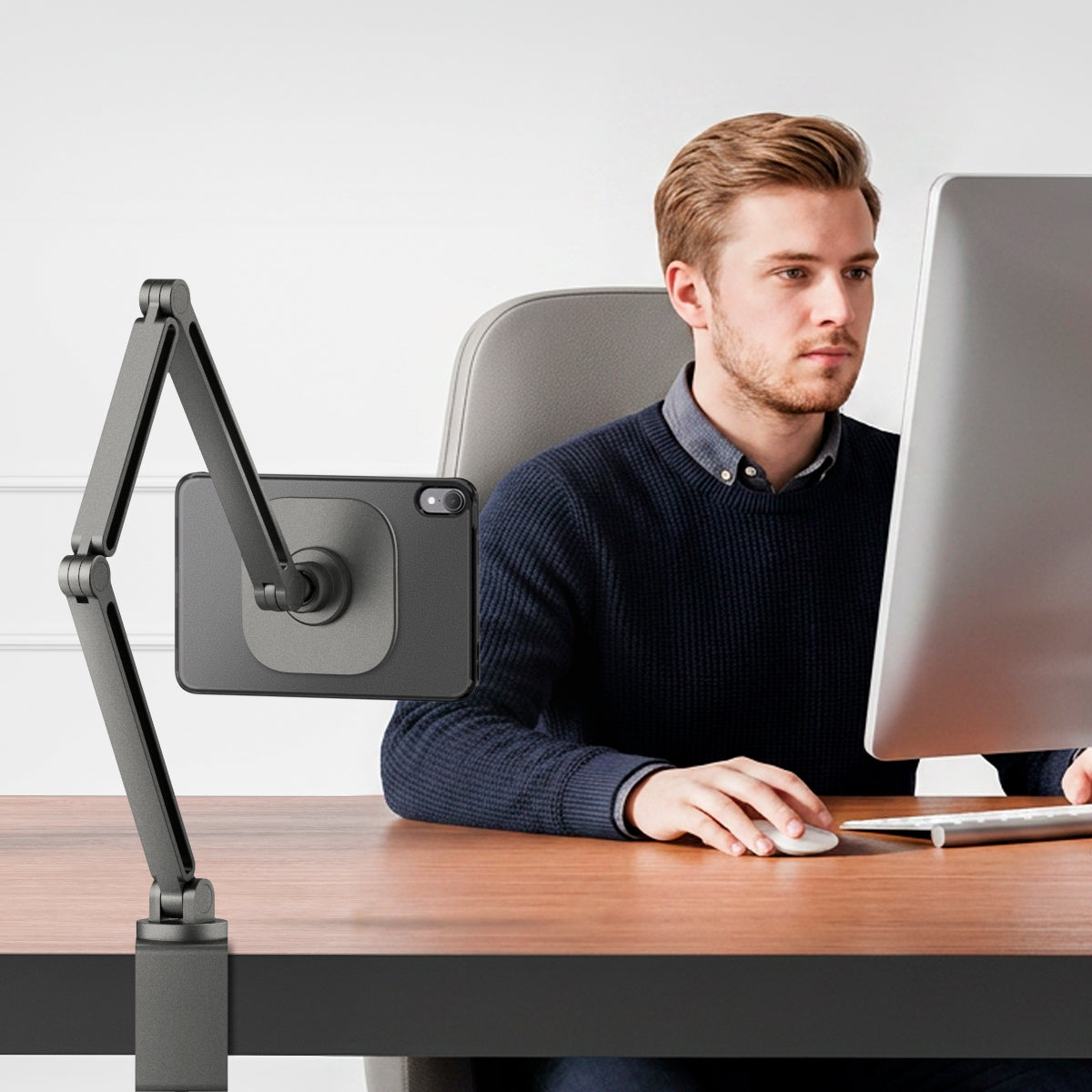 ACS11624 - Man working at a desk with an iPad Mini in the frost black Spigen case mounted on an adjustable articulating arm