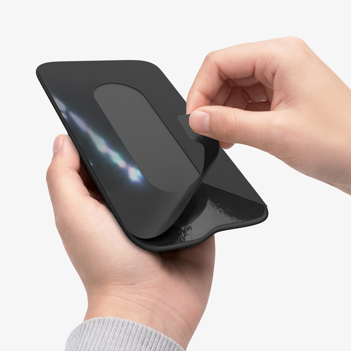 APP11228 - SSD/HDD Holder | LD221 in Black showing hands peeling adhesive backing with flexible fabric pouch stretching open for SSD insertion