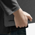 ACS11541 - MacBook Neo 13-inch Urban Fit in Black showing close up of case tucked under arm, logo detail visible