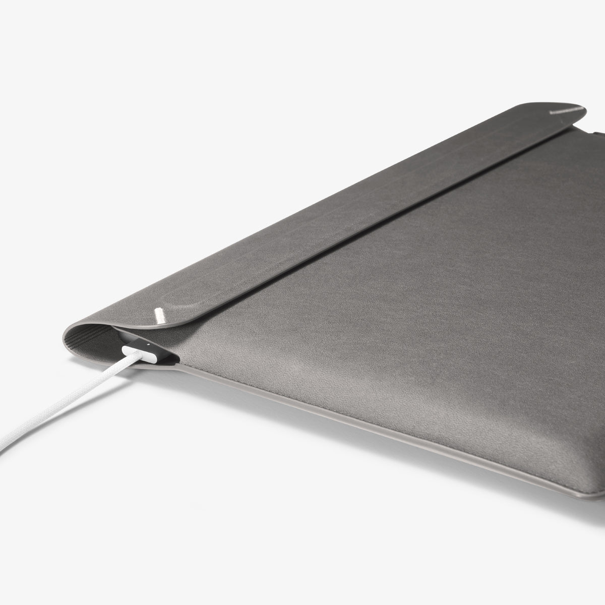 AFA06418 - Spigen Valentinus MacBook Sleeve side profile showing slim leather design with device inside and charger connected