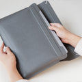 AFA06418 - Spigen Valentinus MacBook Sleeve side profile showing slim leather design with device inside and person taking out of case