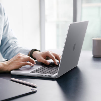 ACS11526 - MacBook Pro 16-inch Air Skin in Frost Clear showing a person typing on a MacBook with the Frost Clear case applied, placed on a desk in an office setting