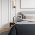 AMP09191 - OneTap Clamp in Space Gray showing the clamp stand with the device attached, clamped to a night stand beside the bed