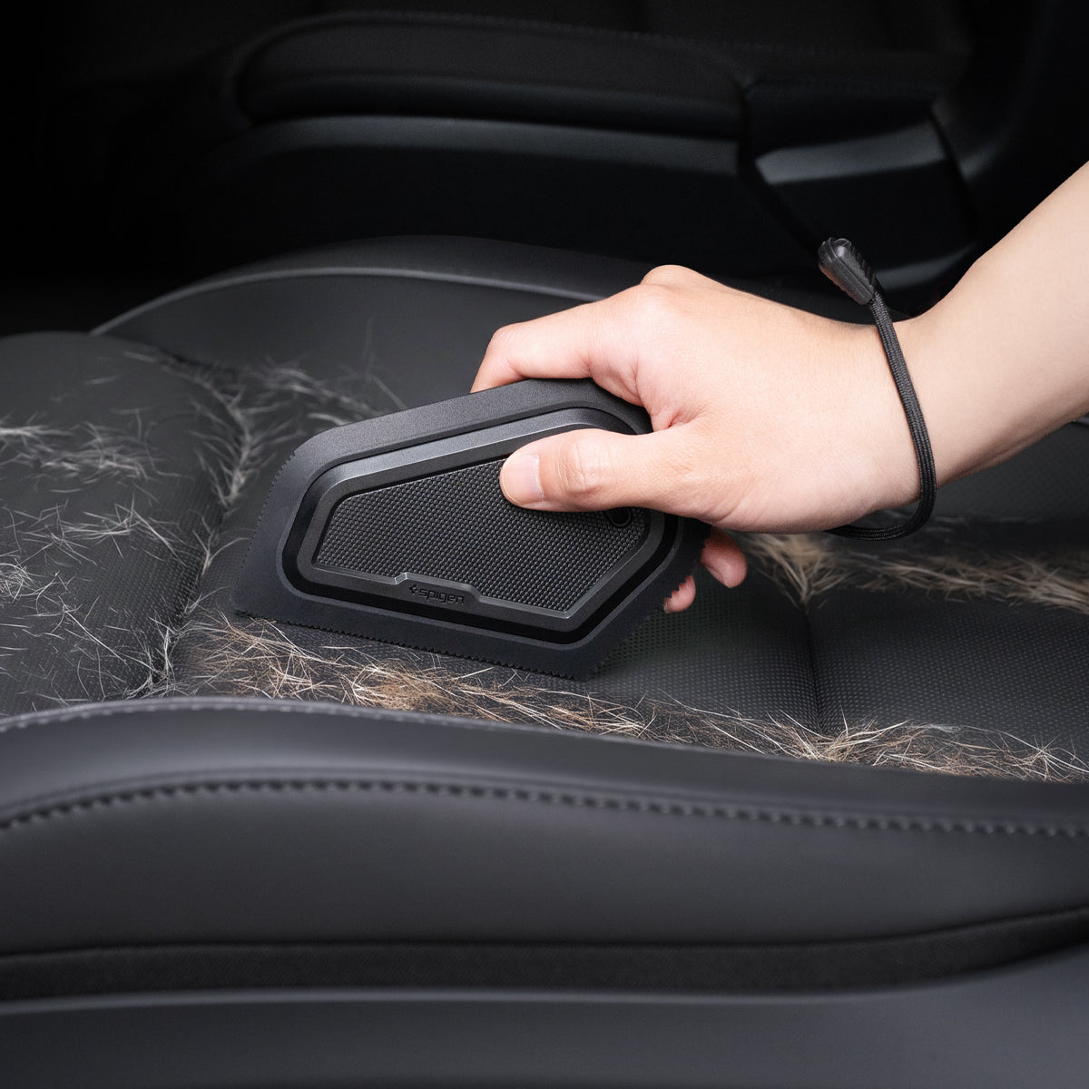ACP11829 - Hand using the Spigen scraper to remove pet hair from a car seat