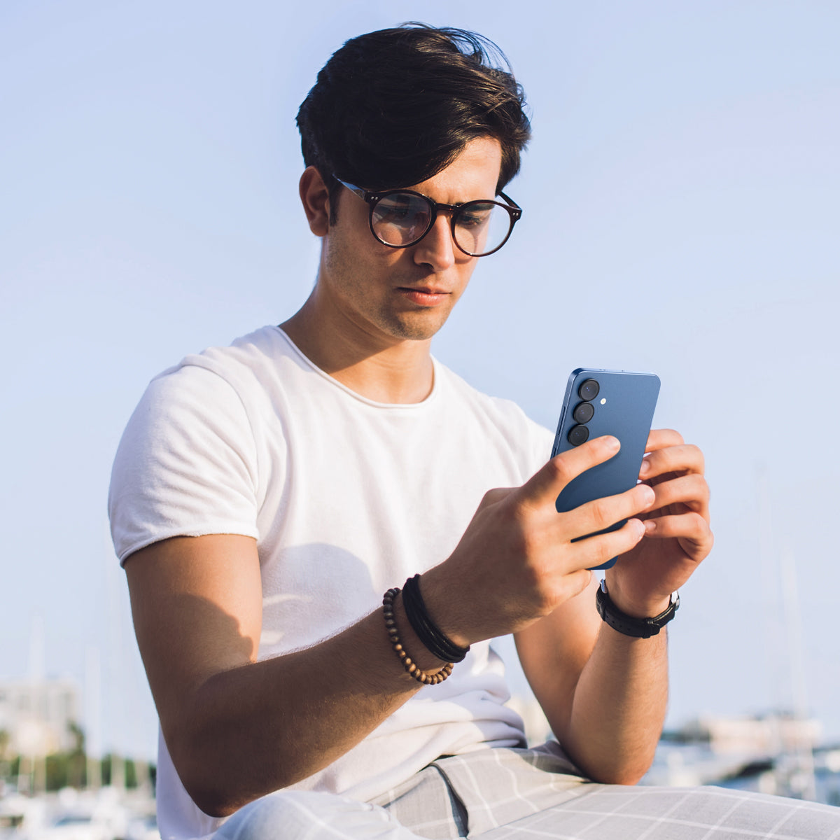 AGL09090 - Galaxy S25 Optik Pro EZ Fit Lens Protector in Black showing a person holding the device