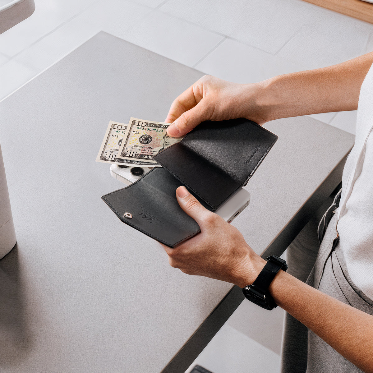 AFA09442 - MagSafe Card Holder Valentinus Pro | 3 Cards in Black showing a person taking out the bill from the wallet