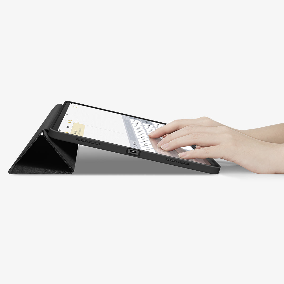 ACS07671 - iPad Air 12.9-inch Case Urban Fit in Black showing the partial front with a hand typing on the device with a folded front cover propped up as a stand