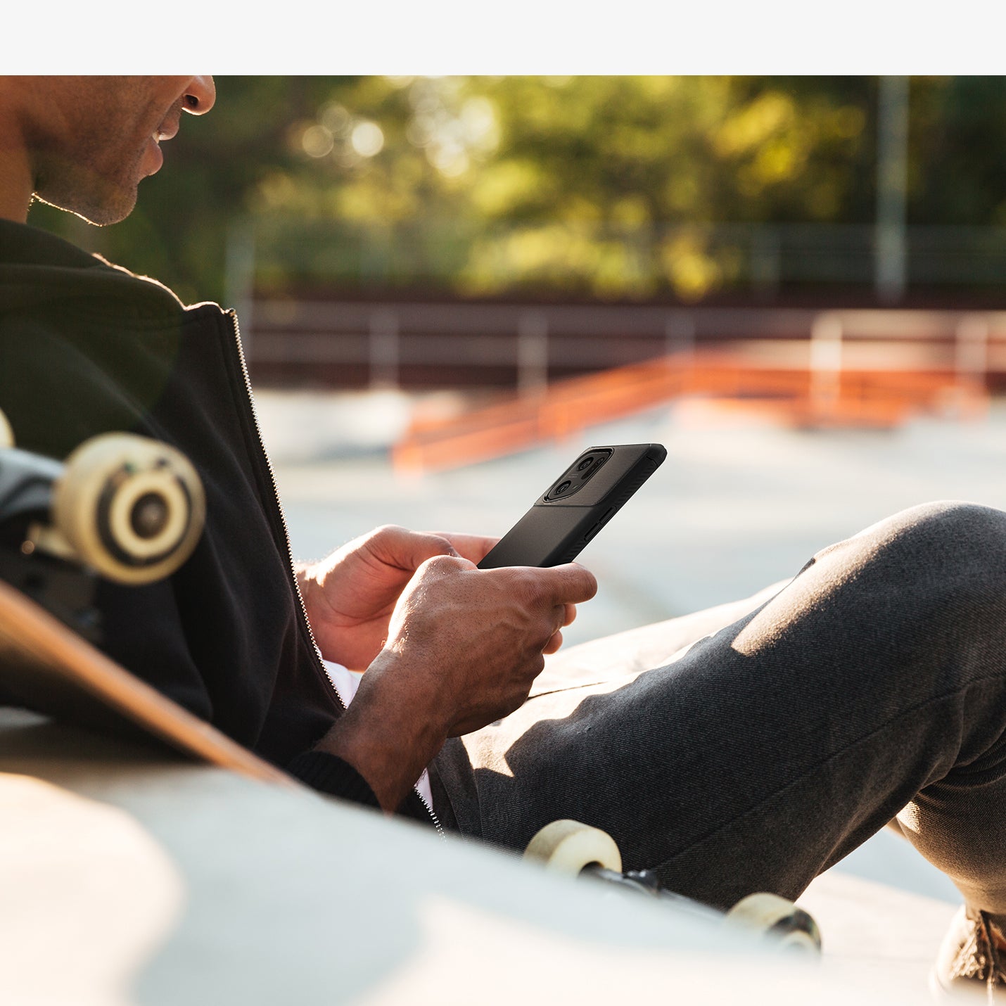ACS04452 - OPPO Find Series Case Rugged Armor in black showing a man sitting at a skatepark with device in hand