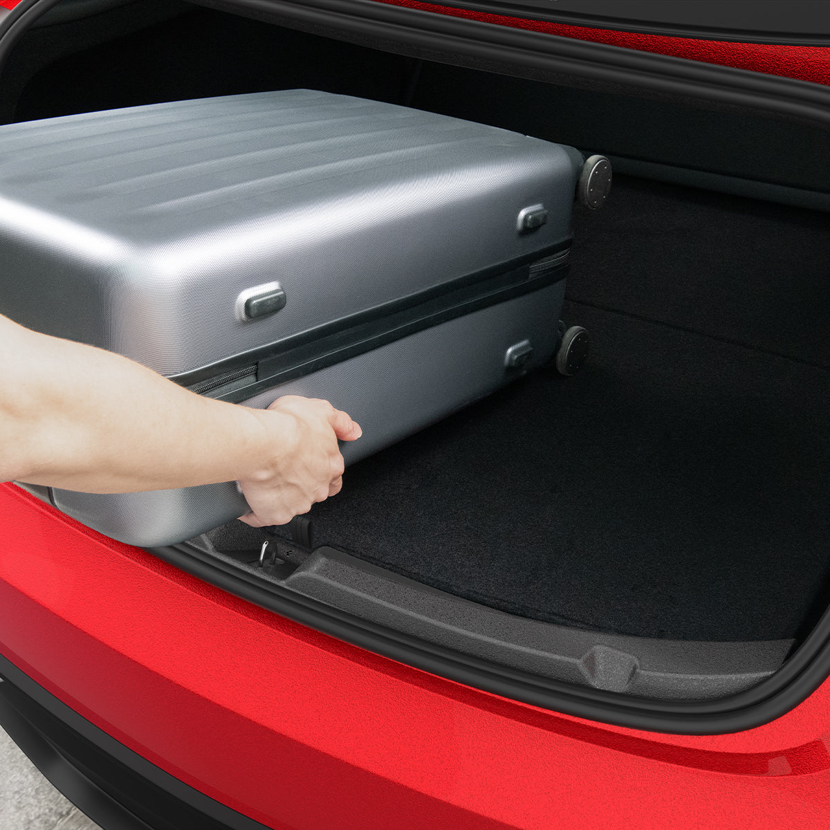 ACP11540 - Hand loading a silver suitcase into a Tesla trunk protected by the black Spigen bumper scuff plate