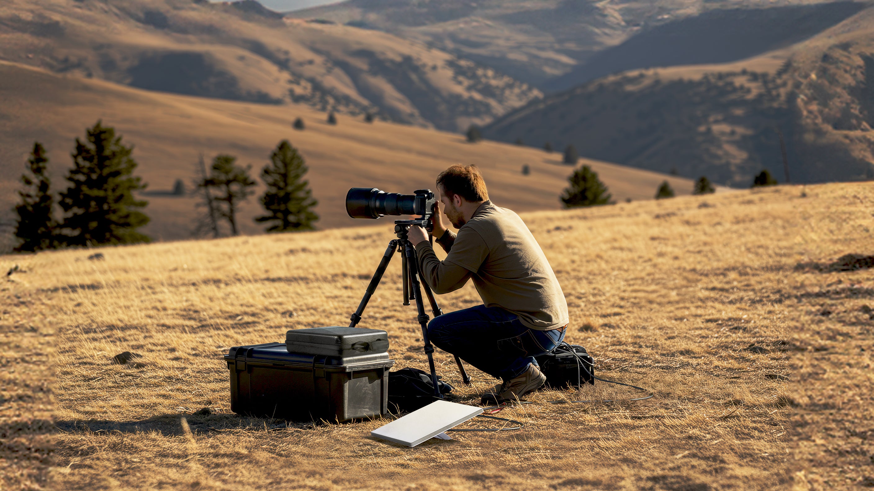 Man kneeling and taking photo on tripod outside with starlink case next to him.