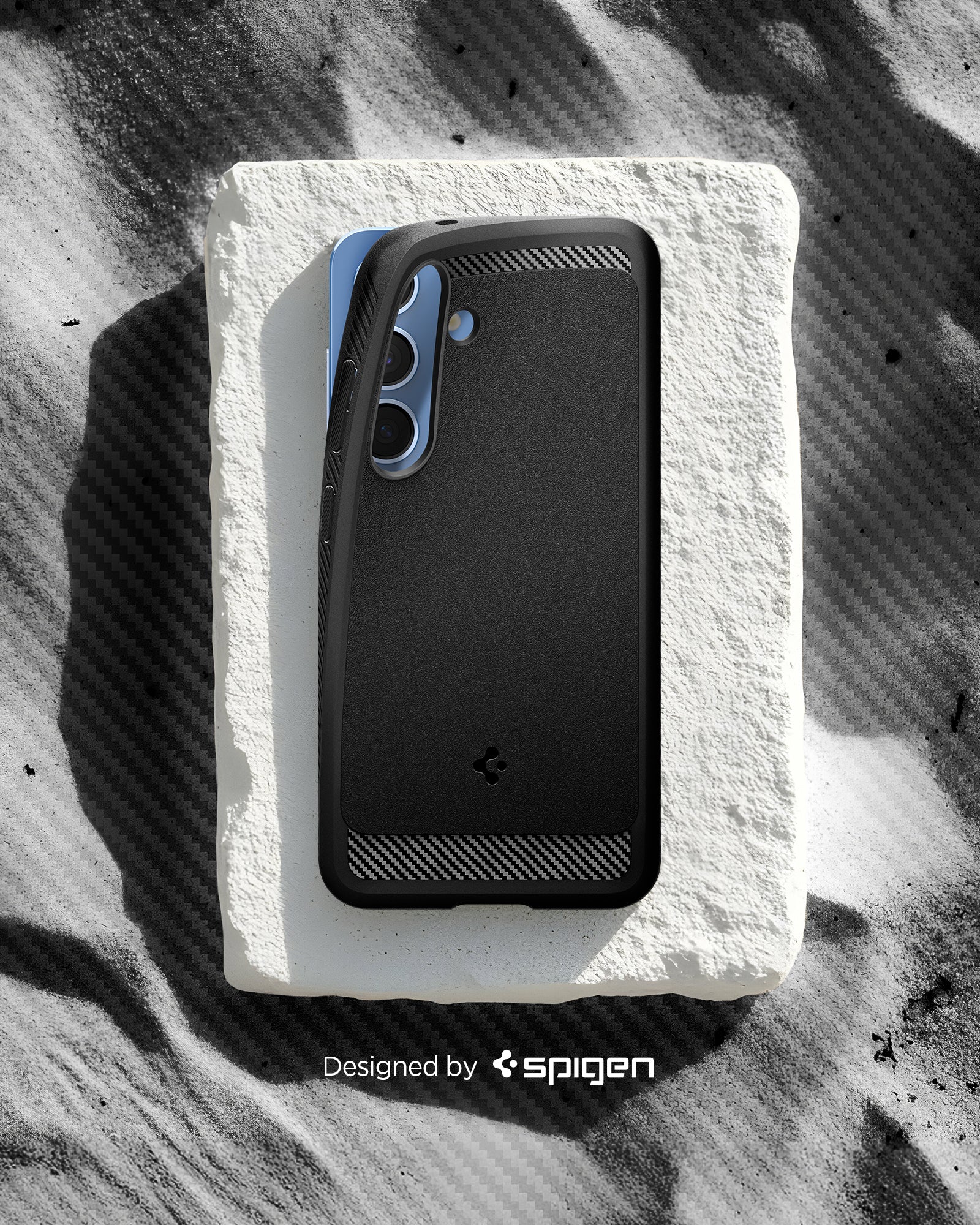ACS08977 - Galaxy S25 Plus Case Rugged Armor (MagFit) in Matte Black designed by spigen. Showing the phone with the pattern on the sand. 