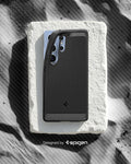 ACS08951 - Galaxy S25 Ultra Case Rugged Armor (MagFit) in Matte Black designed by spigen. Showing the phone with the pattern on the sand. 