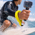AMP11843 - Aqua Shield Floating Strap in Neon Yellow showing a person wearing a floating wrist strap while holding an action camera in the water