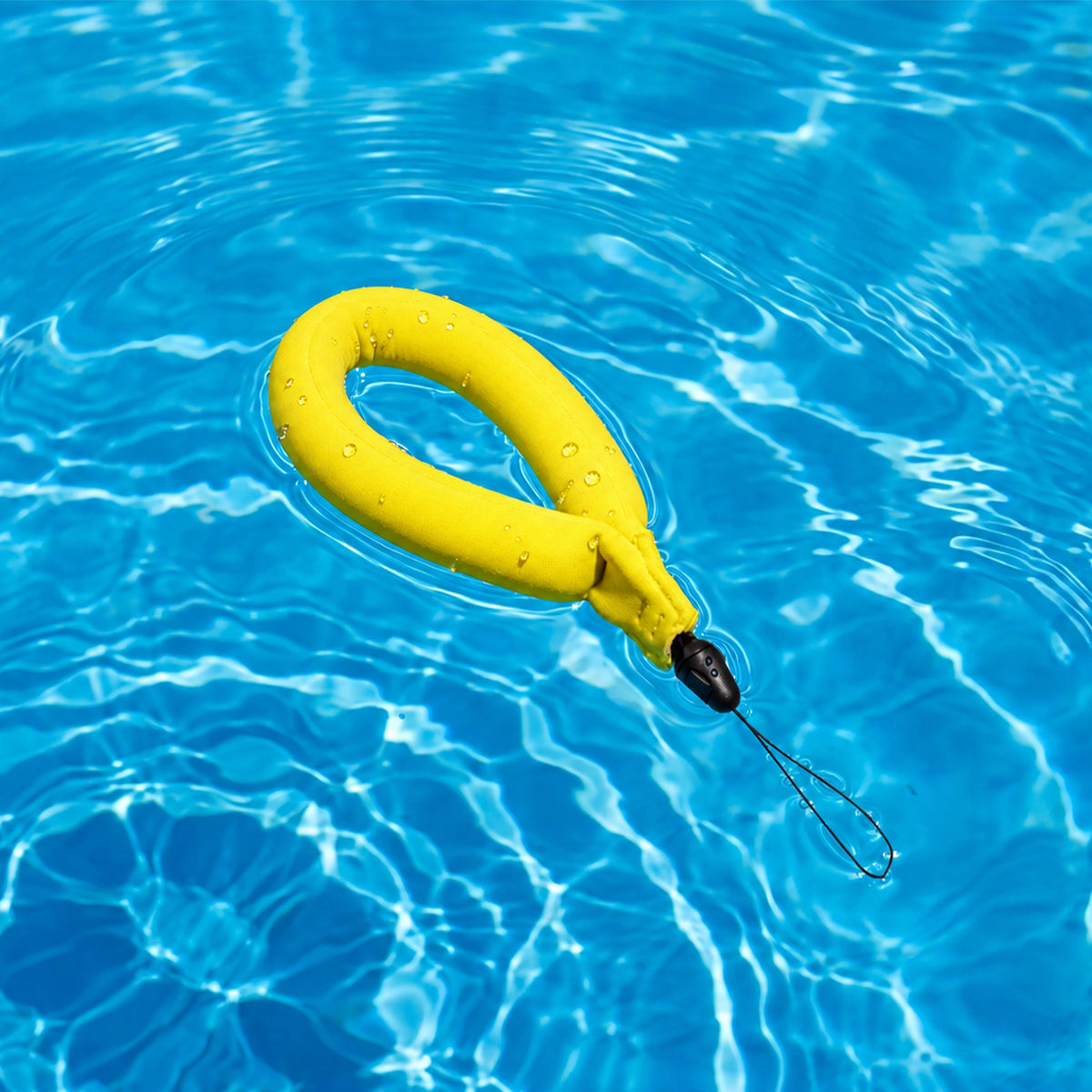 AMP11843 - Aqua Shield Floating Strap in Neon Yellow showing a floating wrist strap resting on the surface of pool water with an attached safety tether