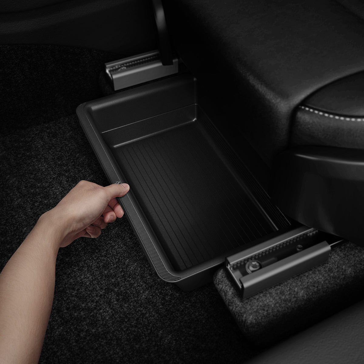 ACP05757 - Underseat Storage Box for Tesla Model Y in black showing a hand installing it inside of car