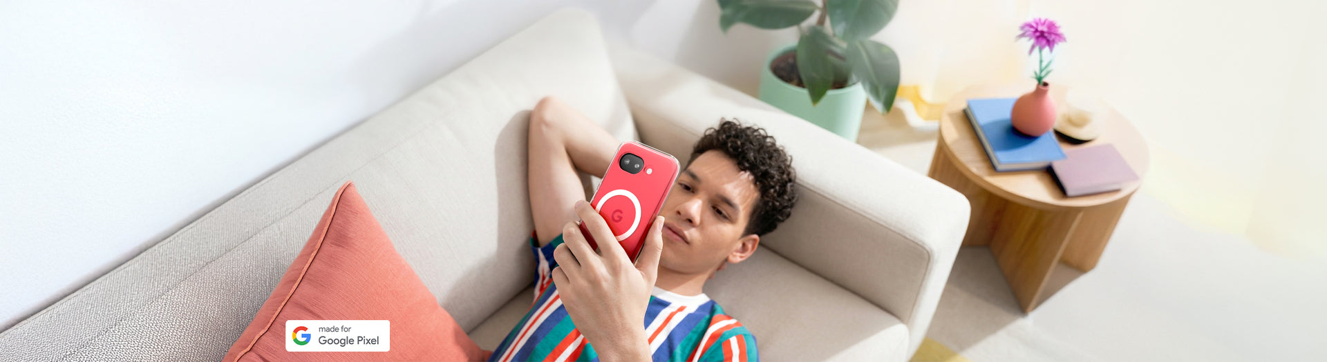 Person relaxing on a sofa holding Pixel 10a with Clear Case and circular MagFit ring design, lifestyle setting with side table and plant in background