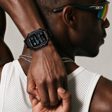 Man wearing a rugged Spigen Apple Watch case with a digital watch face showing the time, temperature, and battery, paired with sunglasses and a mesh tank top