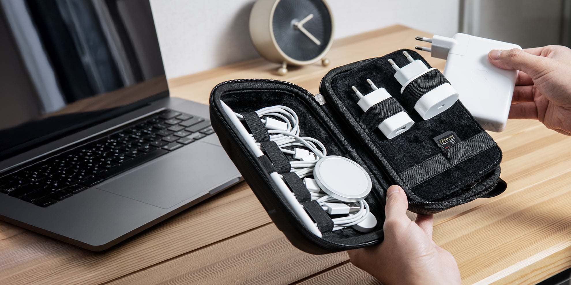 Showing hands holding a cable organizer with wall chargers and electronic cables.