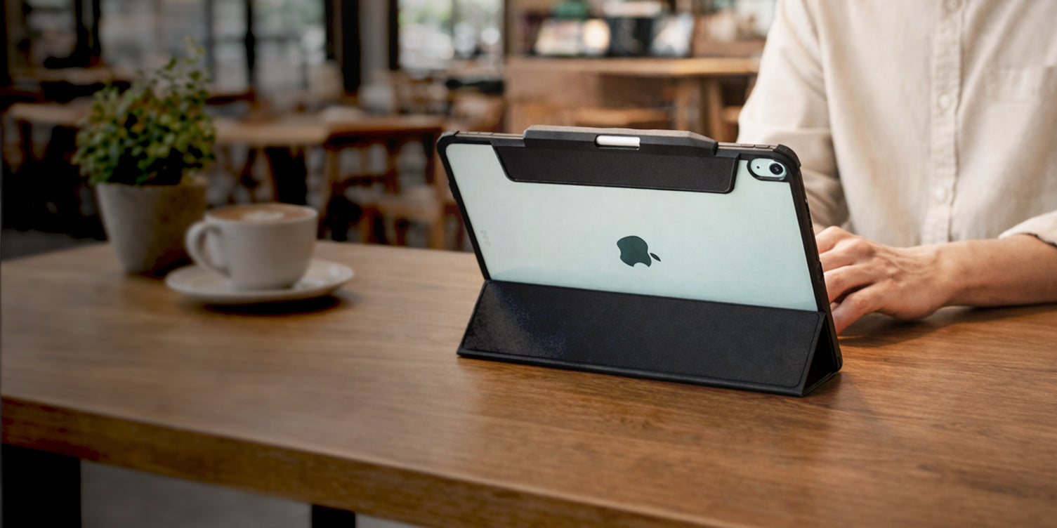 Spigen iPad Air Case propped in stand mode on wooden table with user working in cafe setting