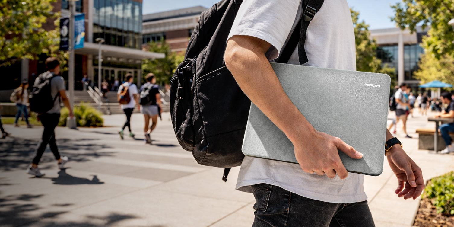 Spigen MacBook Sleeve carried under arm on campus walkway with backpack and students in background