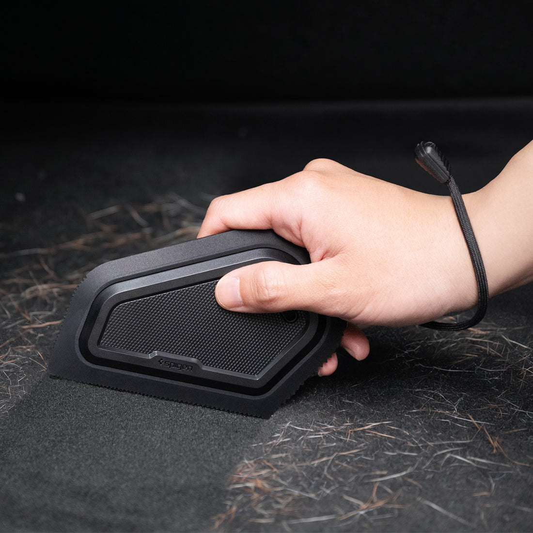 ACP11829 - Hand holding the Spigen car detailing scraper over a surface covered in pet hair