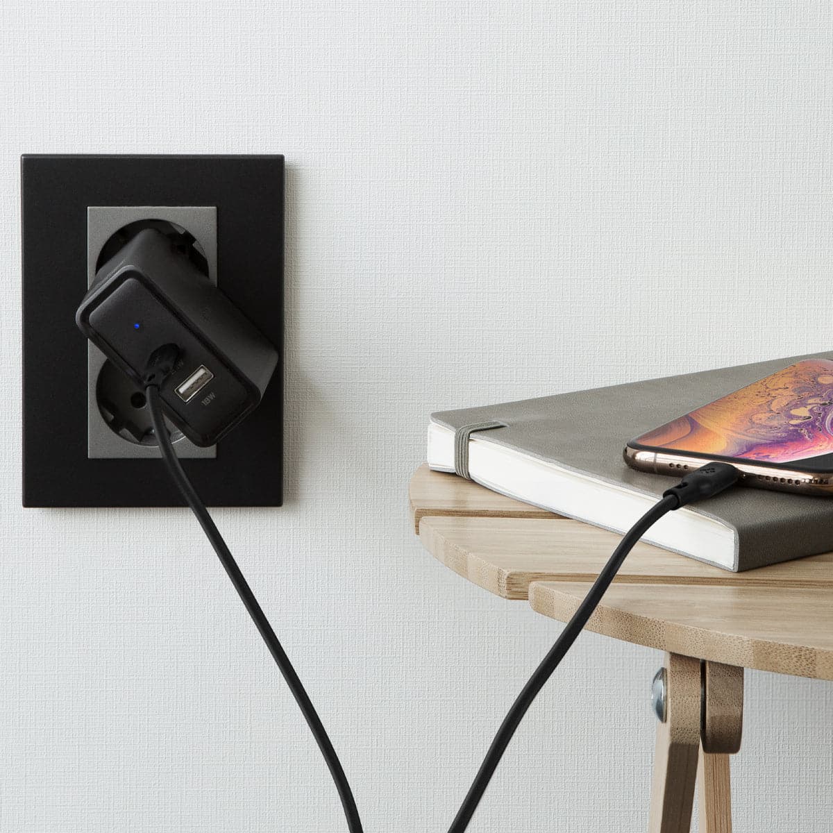 000CA27021 - DuraSync USB-C to Lightning Cable in black showing the cable connected to a wall charger and charging a phone