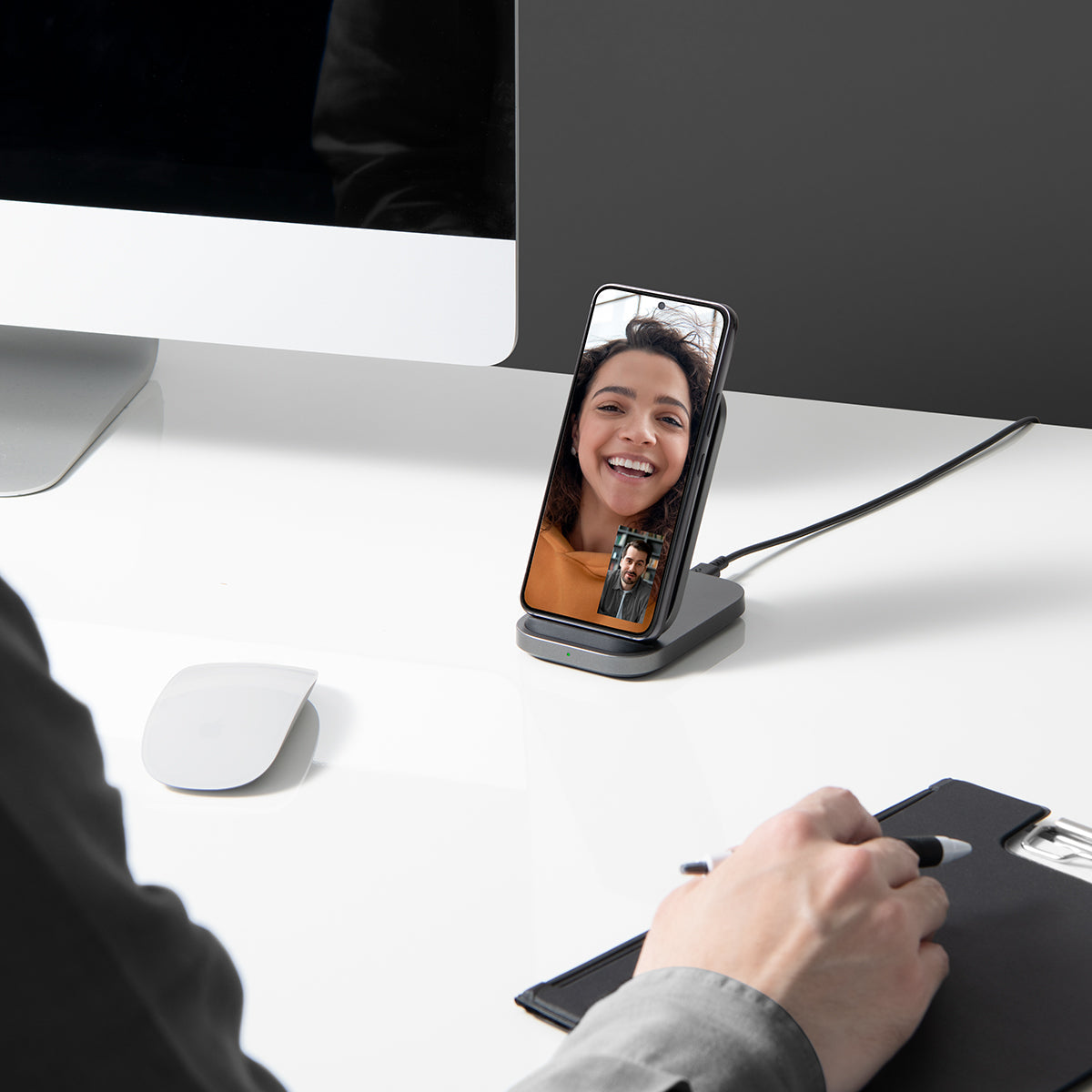 ACH06254 - ArcField PF2102 Wireless Charger in black showing the wireless device on a computer desk with a Samsung device charging while on a facetime video call