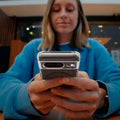 ACS06281 - Pixel 8 Case Ultra Hybrid Metal Ring (MagFit) in black showing a woman sitting outside with device in her hand