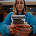 ACS06318 - Pixel 8 Pro Case Ultra Hybrid Metal Ring (MagFit) in black showing a woman sitting outside with device in hand